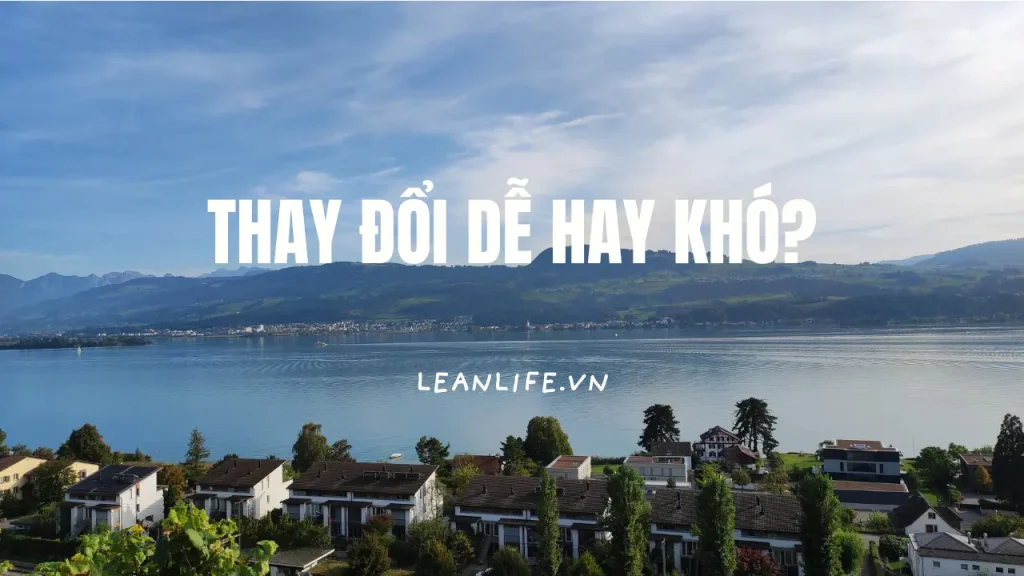 Một hồ nước trong xanh bên xa là đồi núi và phía gần là một dãy nhà