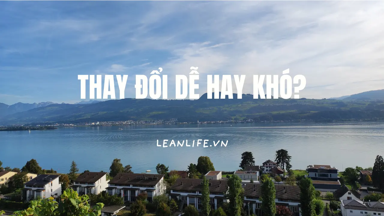 Một hồ nước trong xanh bên xa là đồi núi và phía gần là một dãy nhà